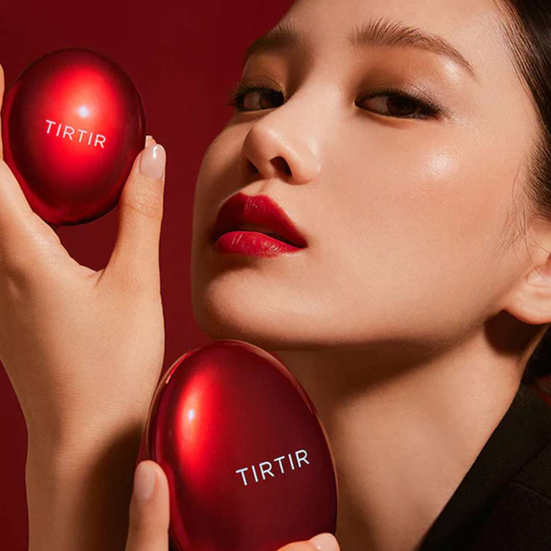 Woman holding two red TIRTIR products against a red background