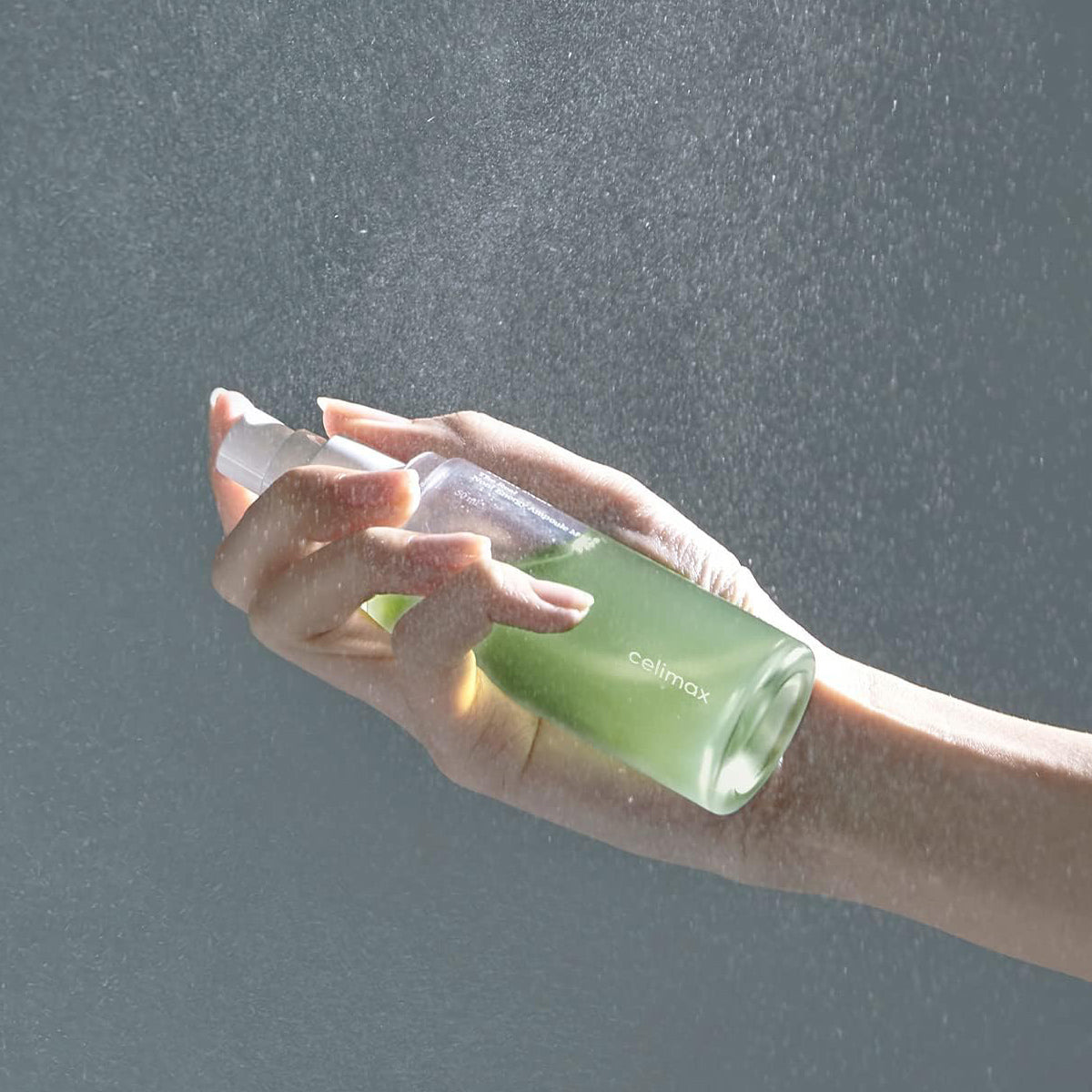 Hand holding a green bottle labeled 'celimex' against a gray background