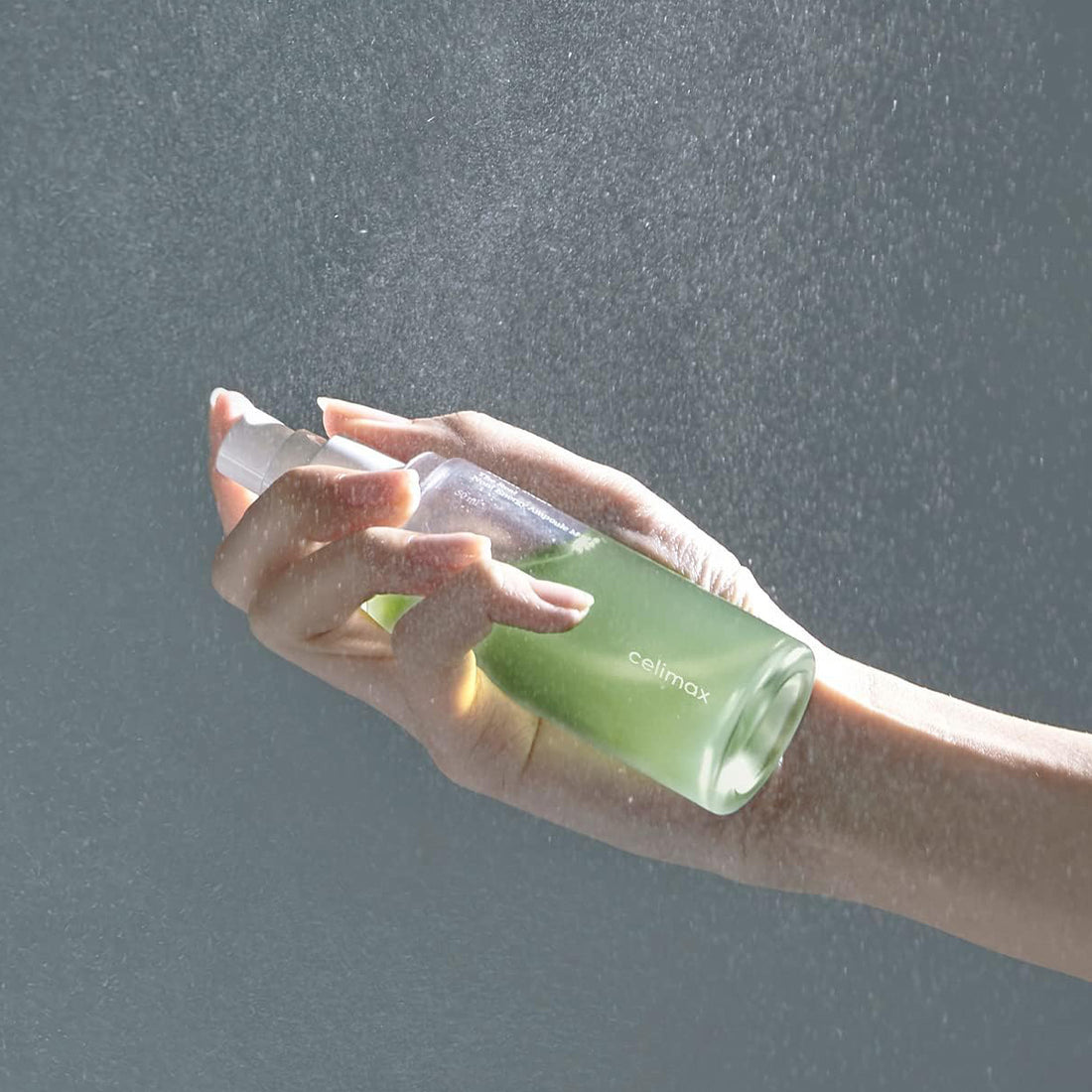 Hand holding a green bottle labeled 'celimex' against a gray background