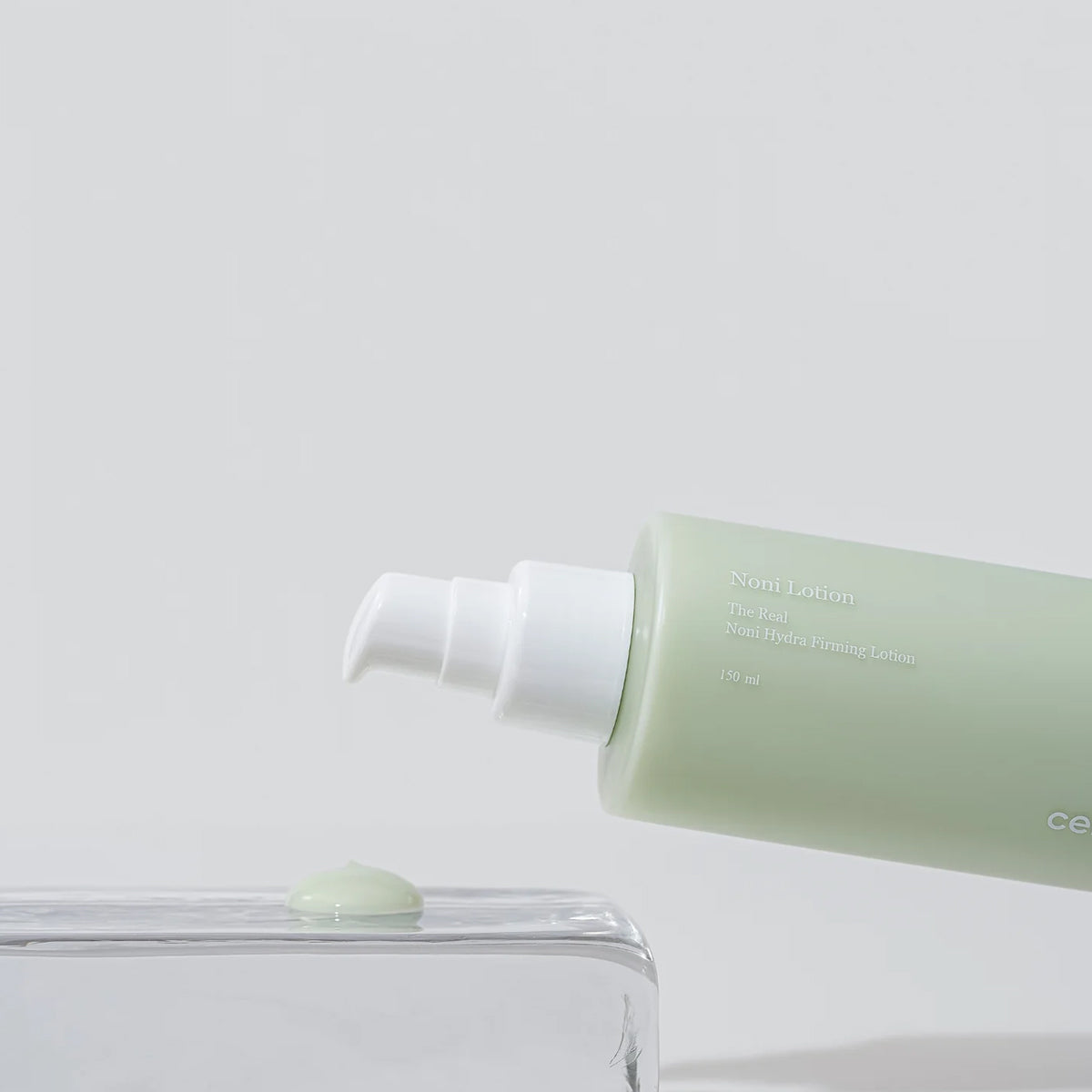 Green lotion bottle with white cap on a light gray background