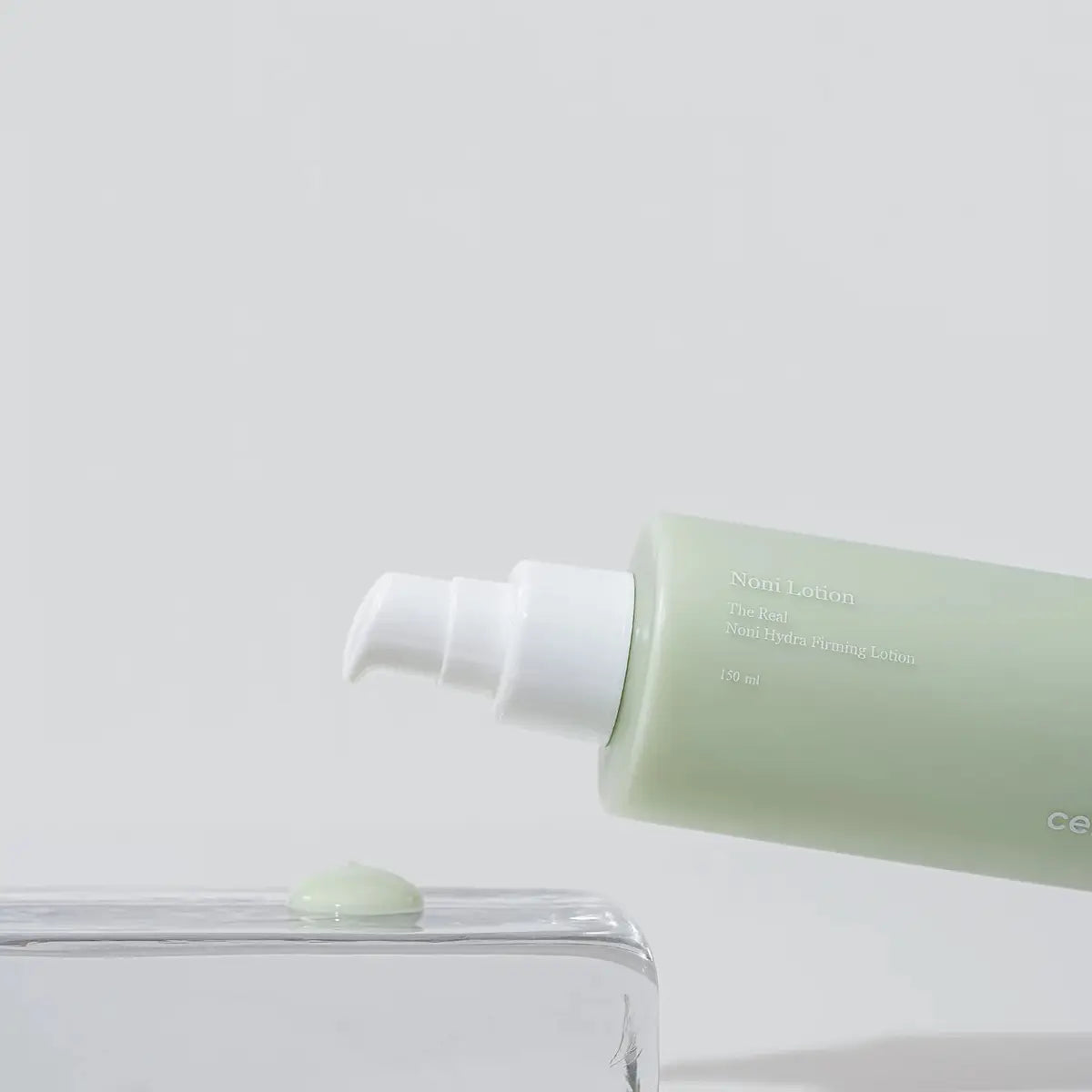 Green bottle of lotion with a white cap on a light gray background
