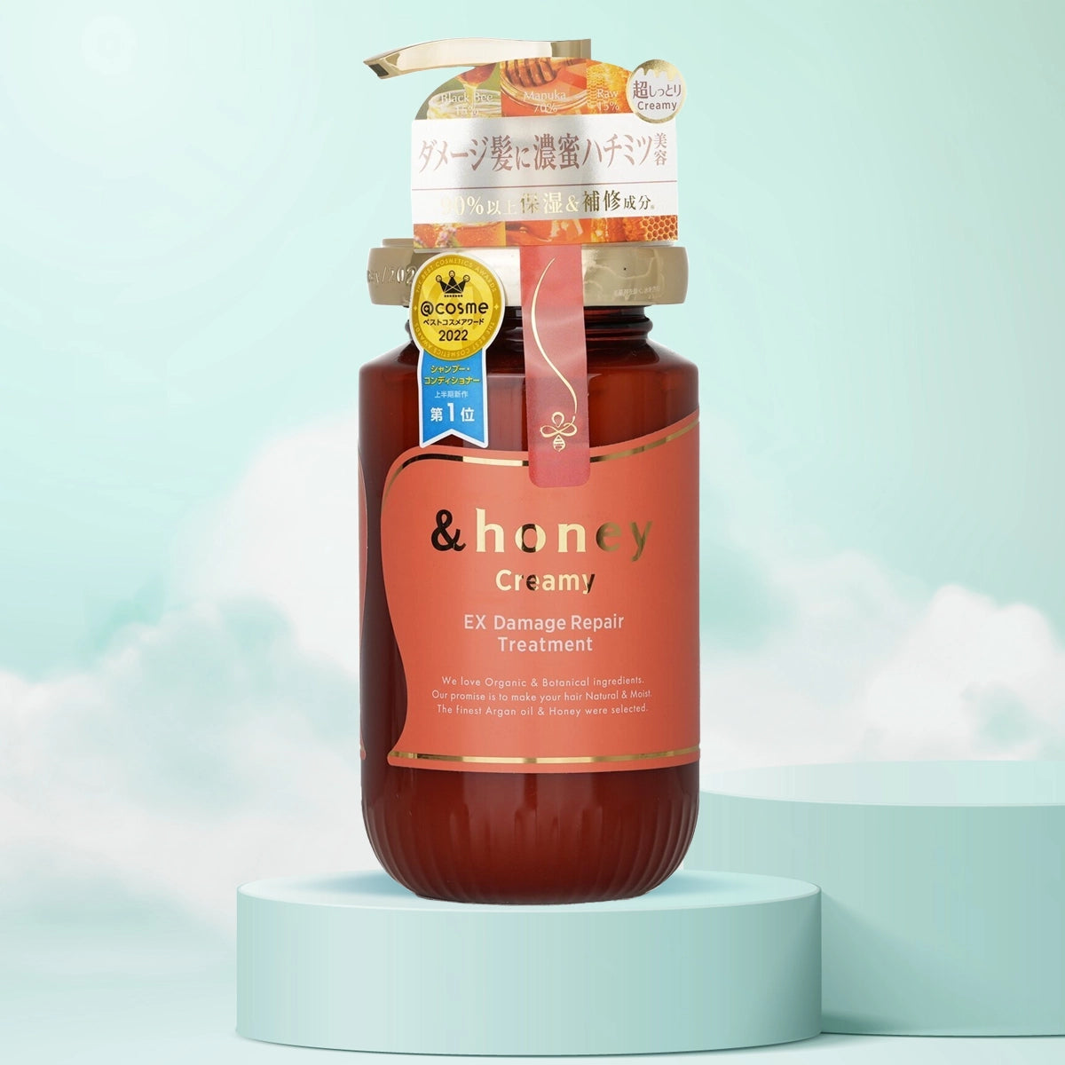 A bottle of &Honey Creamy EX Damage Repair Treatment positioned on a stand with a light blue background, showcasing the product label and cap.