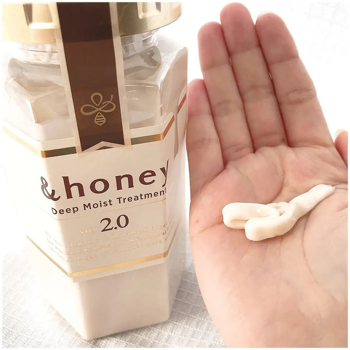 &Honey Deep Moist Treatment 440mL bottle next to a hand holding the creamy treatment