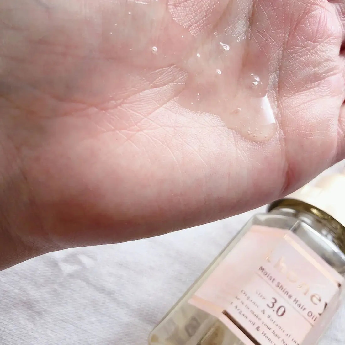 &Honey Moist Shine Hair Oil 100mL in hand, showcasing its lightweight texture and nourishing properties.