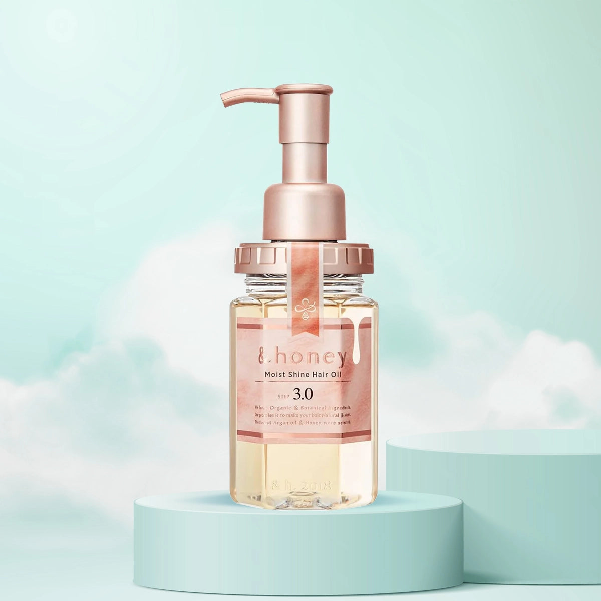 A bottle of &Honey Moist Shine Hair Oil with a pump dispenser, displayed against a pastel background.