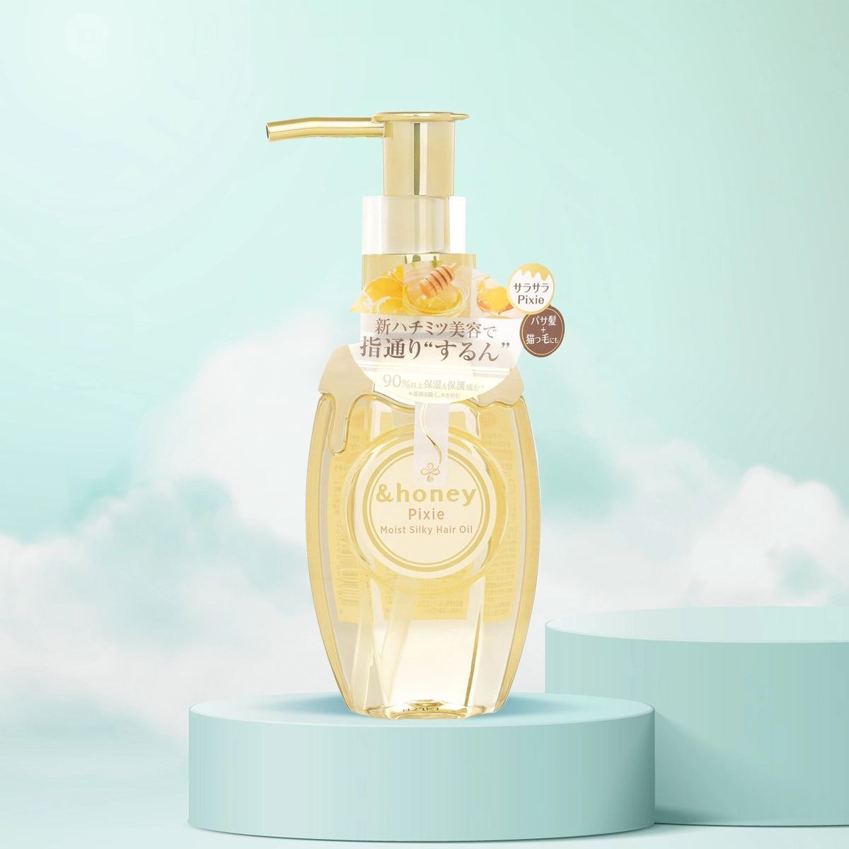 A bottle of &Honey Pixie Moist Silky Hair Oil with a pump dispenser, displayed against a sky blue background. The bottle is transparent with a yellow liquid inside, and it's adorned with a floral and bee-themed label.