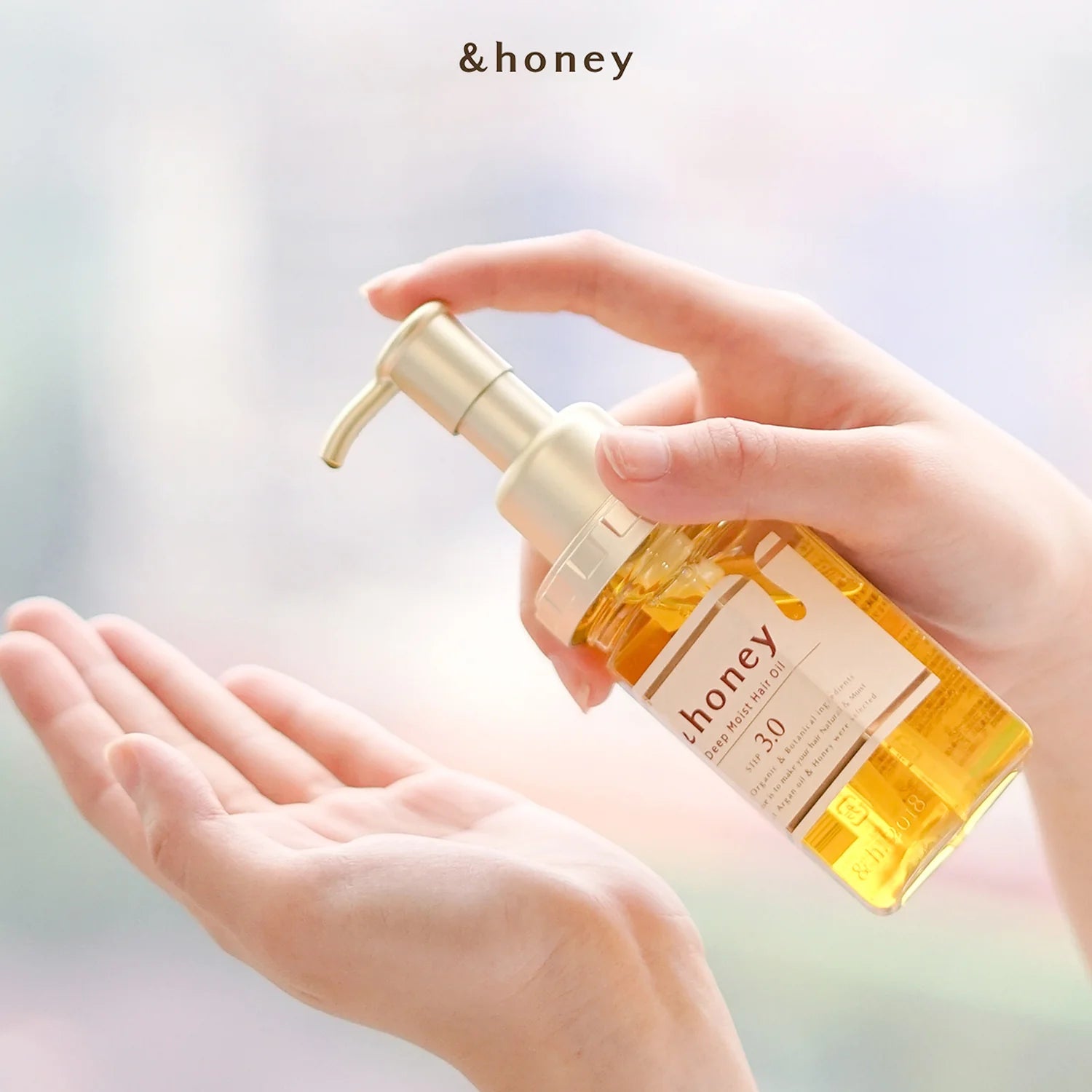 Hand holding a bottle of ViCREA &Honey EX Deep Moist Hair Oil – nourishing Japanese hair oil with honey blend for silky, with a pump dispenser.