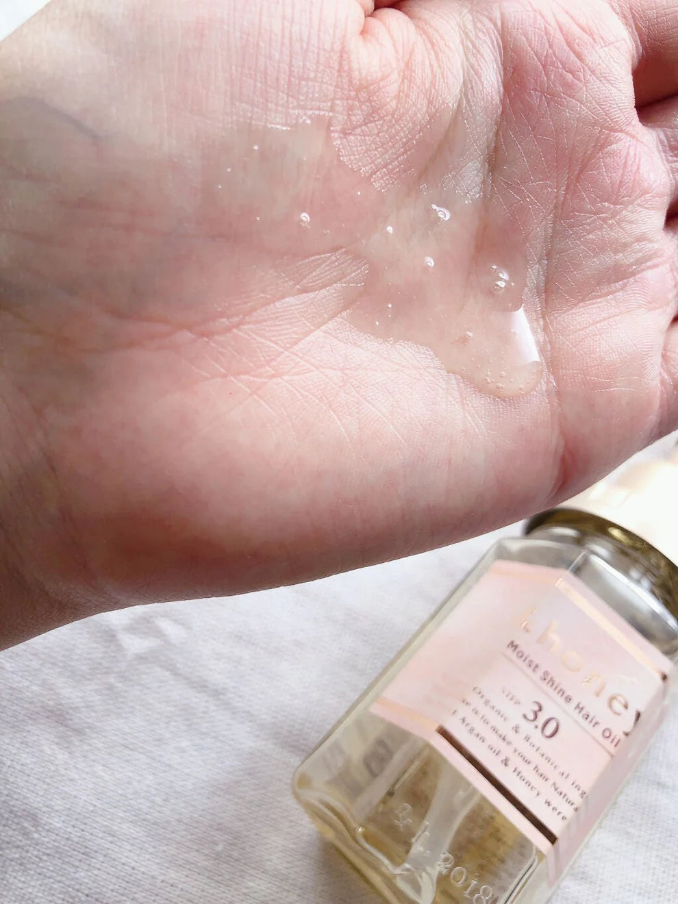 Hand holding a bottle of oil with a close-up view.