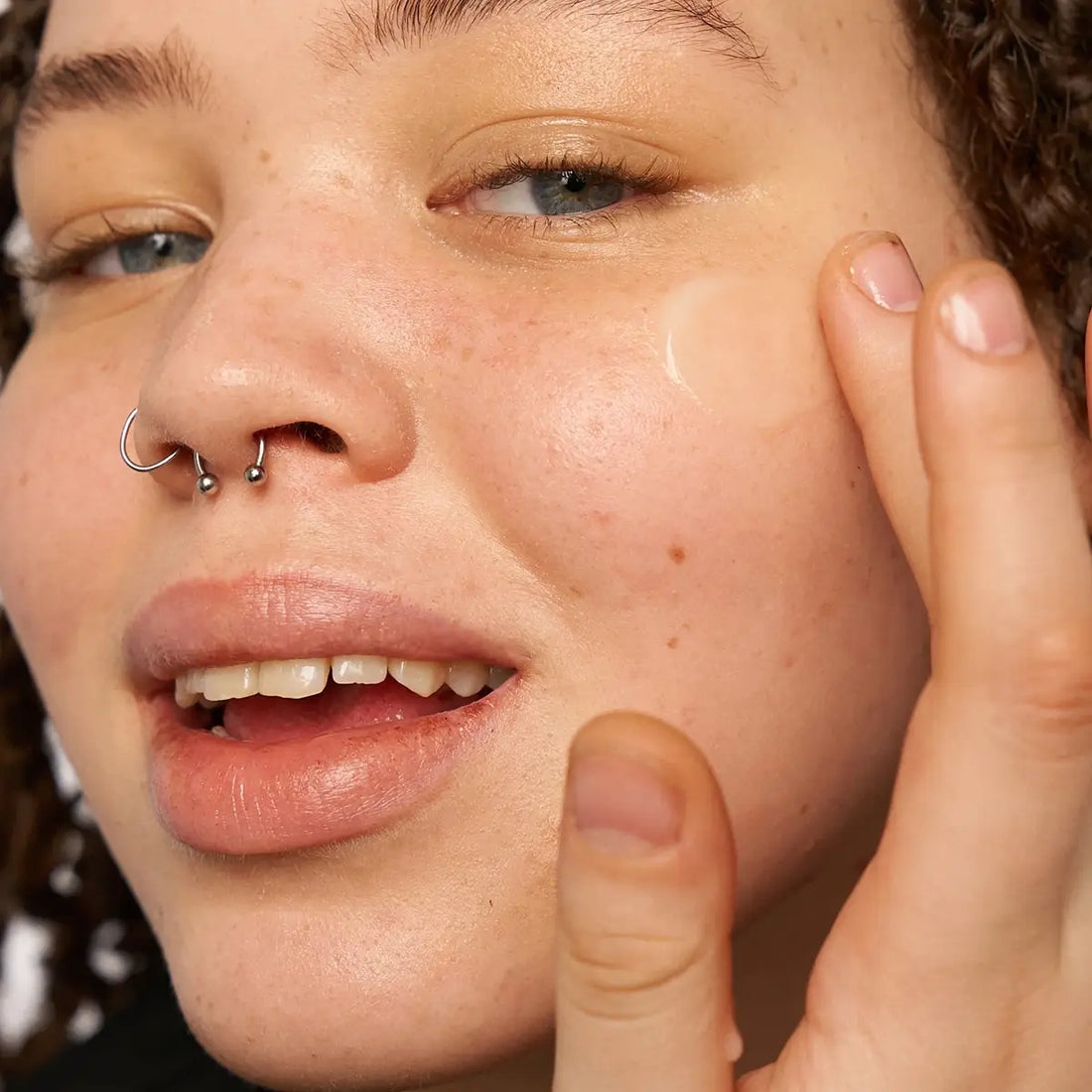 Close-up of a person applying skincare product to their face.
