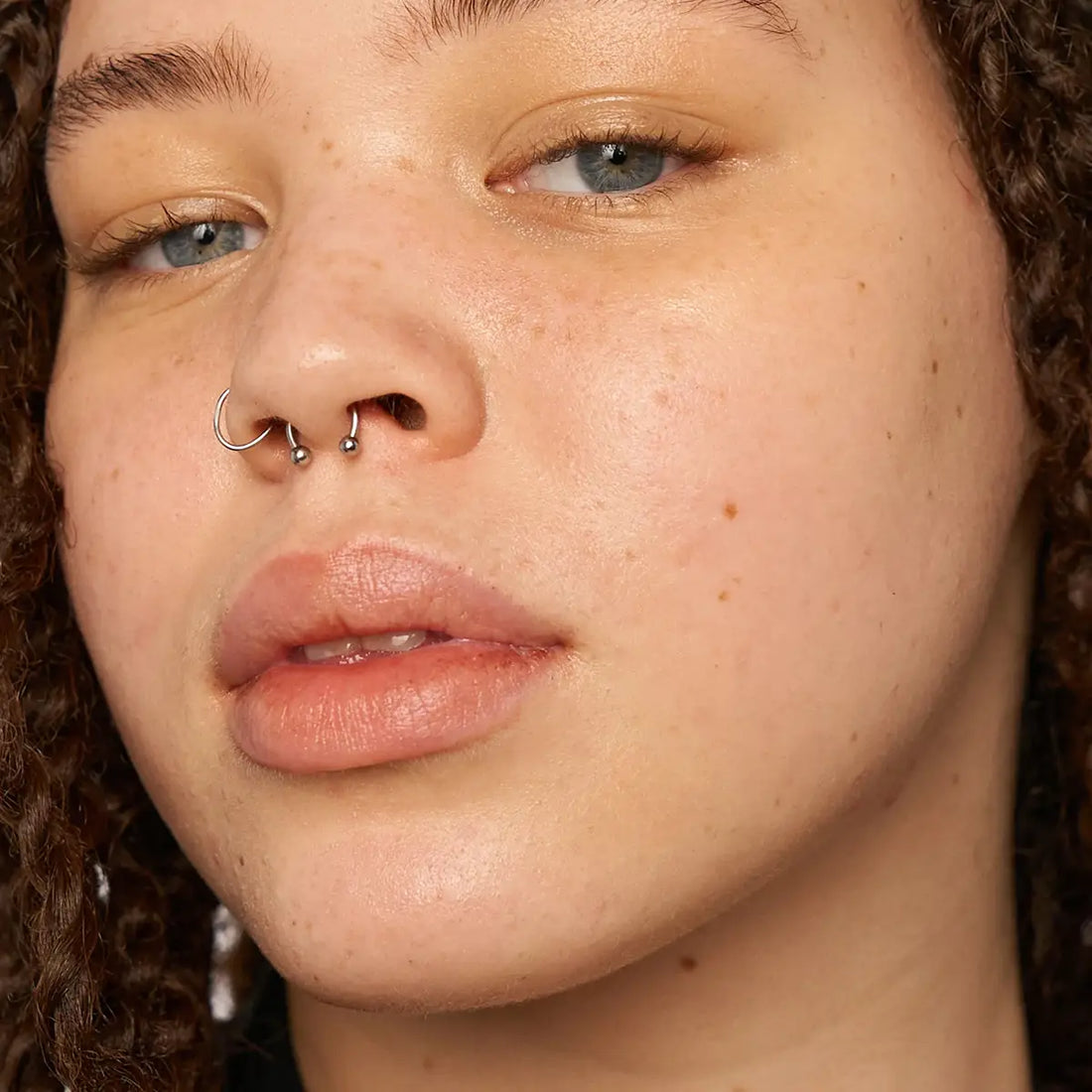 Close-up of a person with a nose ring and earrings.
