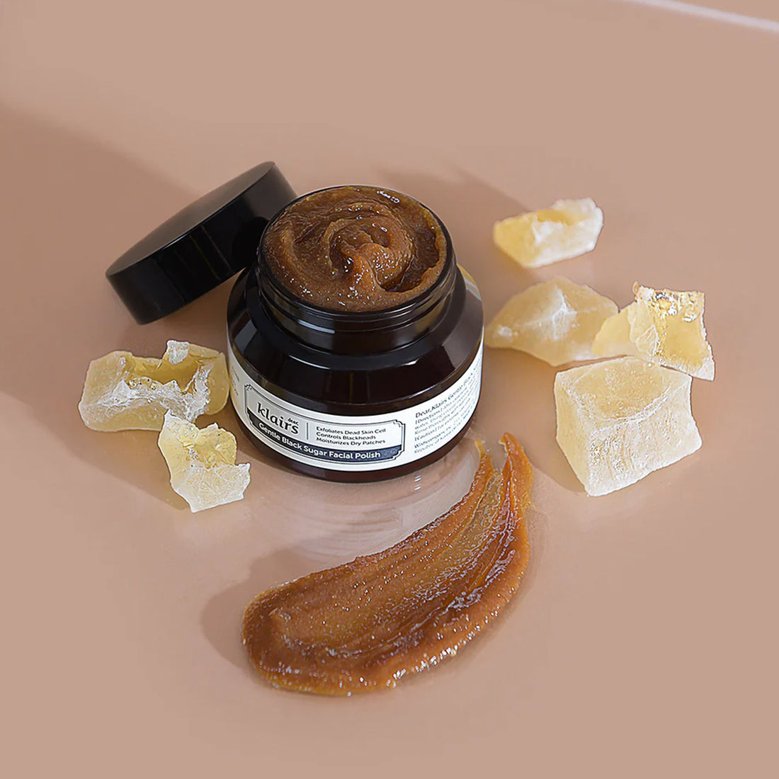Jar of honeycomb extract with pieces of honeycomb on a beige background