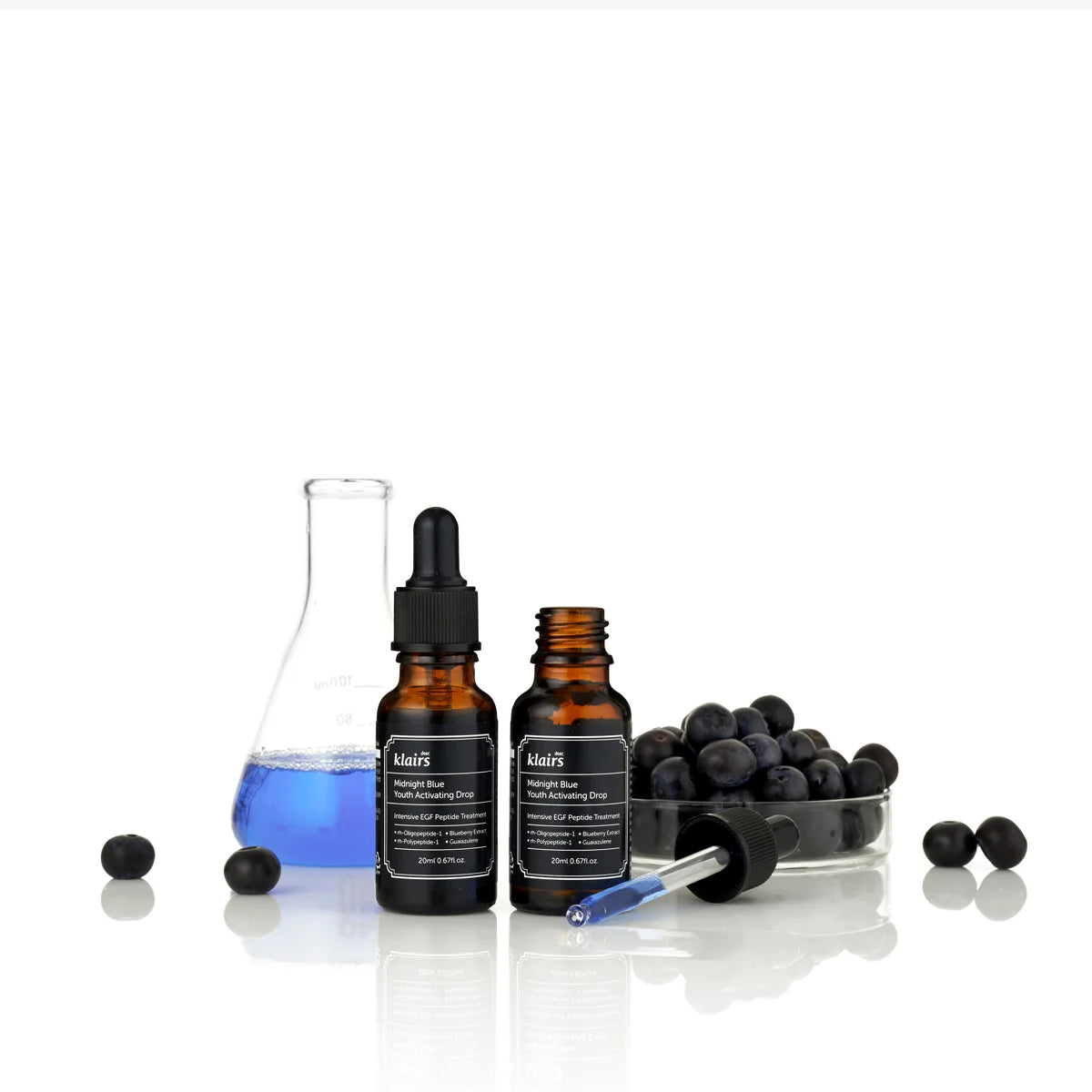 Two bottles of Kiehl's with blue liquid and black berries on a white background