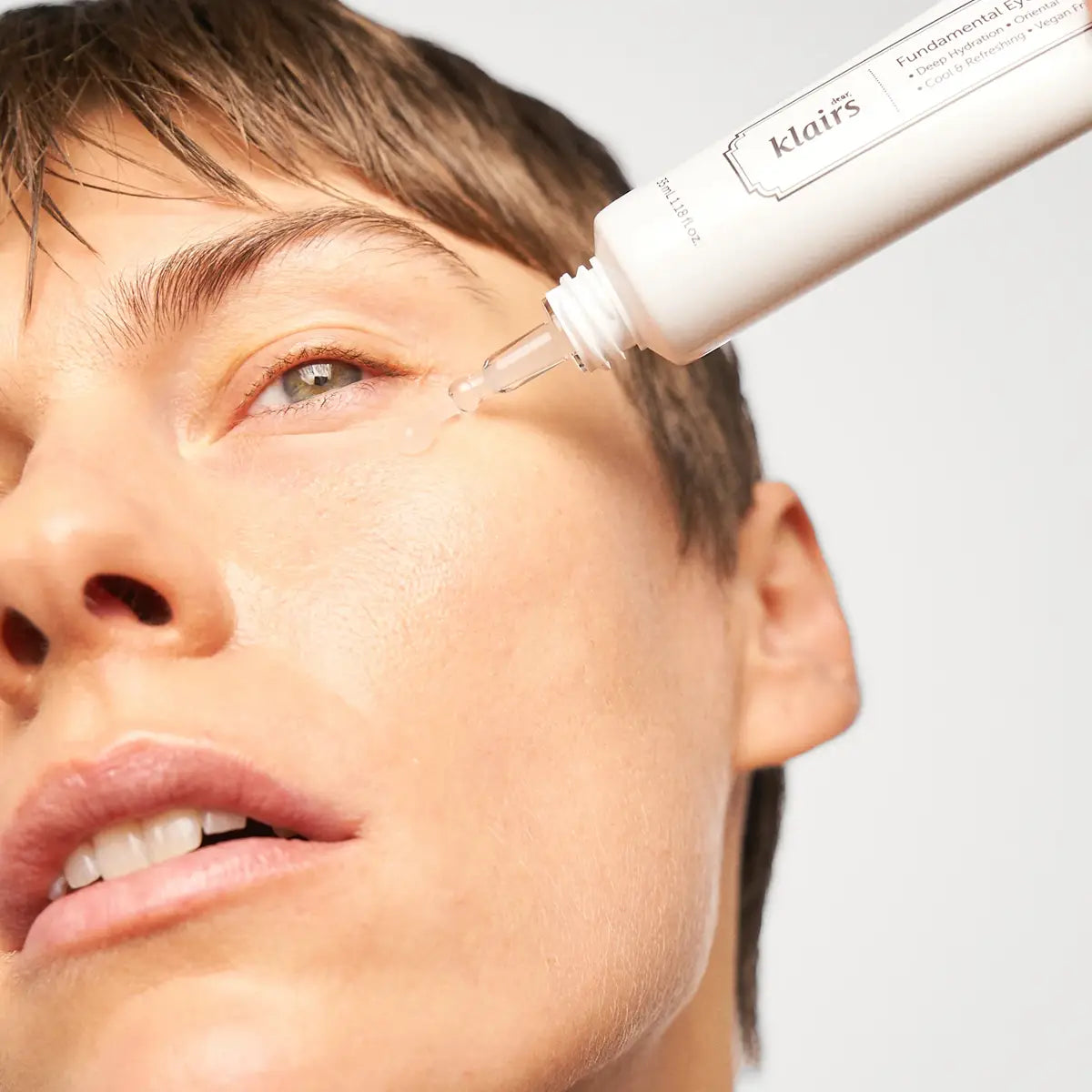 Person applying a dropper of skincare product to their eye with a 'klairs' dropper visible.