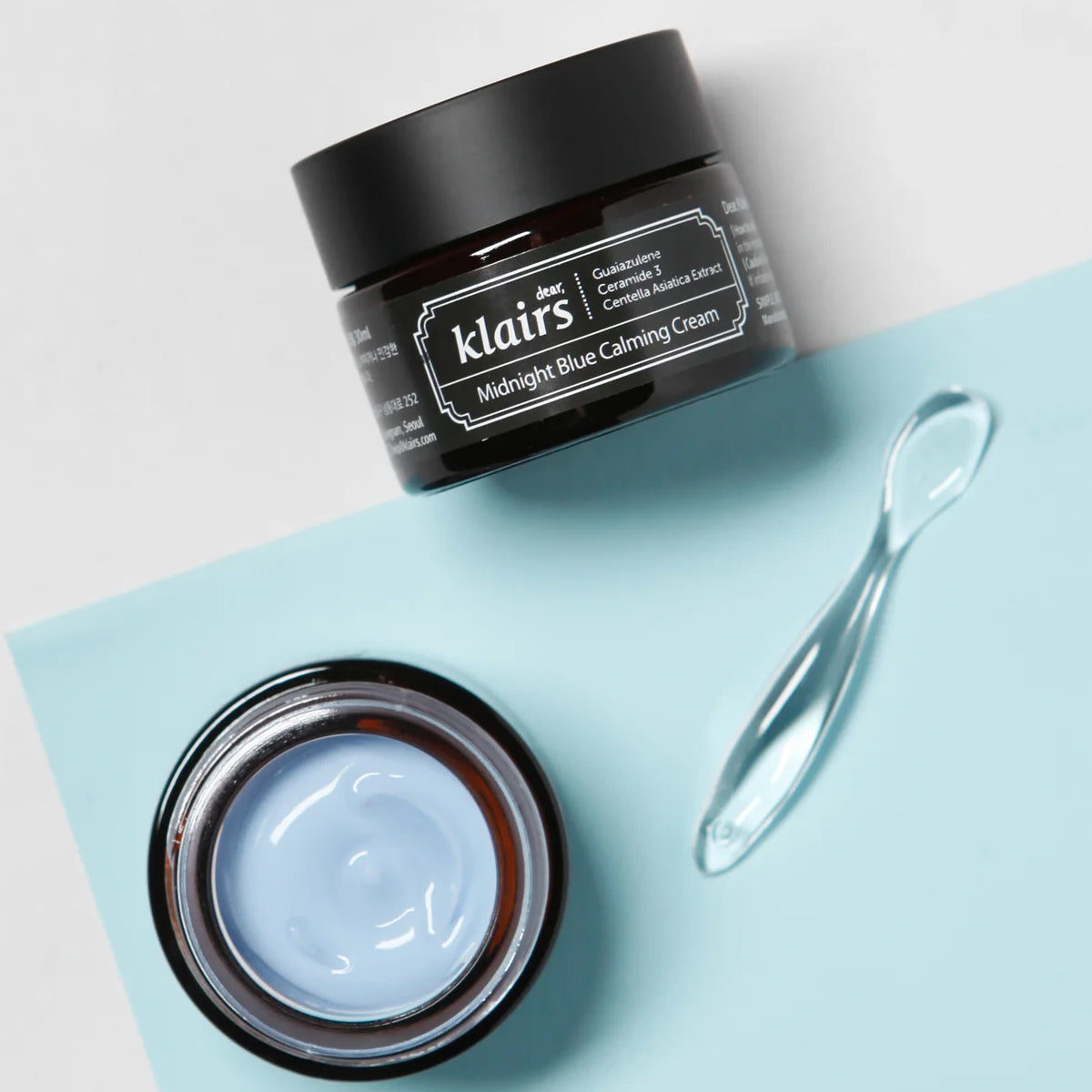 Klairs Midnight Blue Calming Cream jar with open lid on a light blue surface