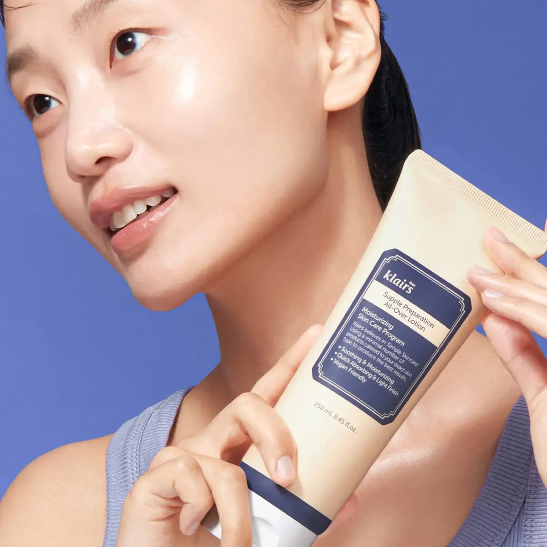 Woman holding a skincare product with a blue background