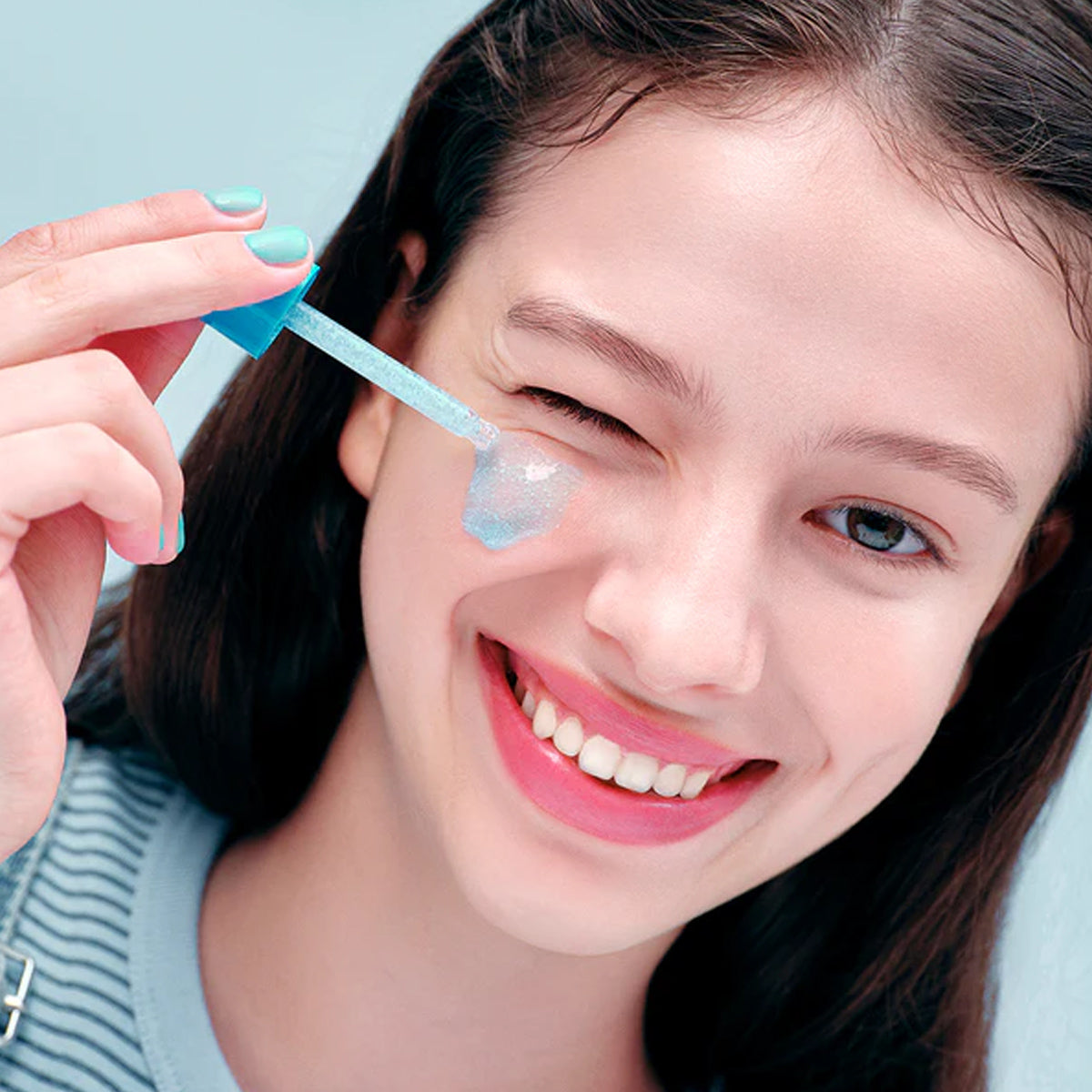Woman applying a skincare product to her face with a applicator.