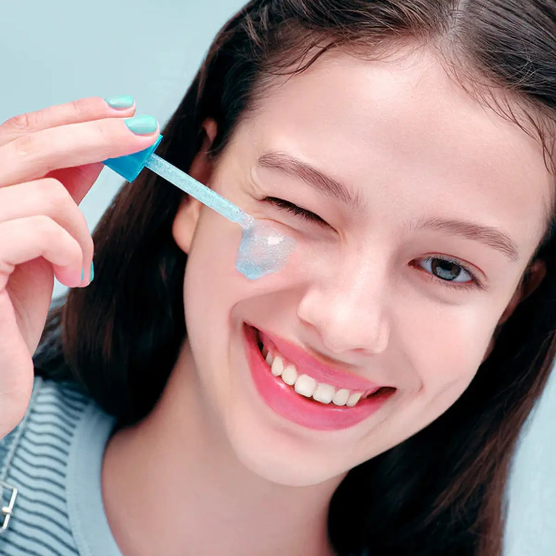 Woman applying a Eqqualberry Hyaltoin Flooding Serum to her face with a blue applicator.